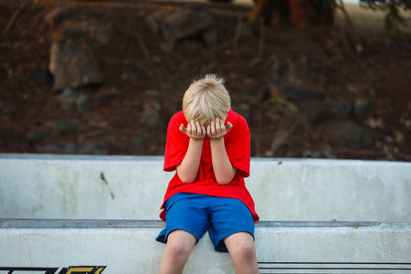 A shallow focus hot of a blond boy with a red T-shirt closing his eyesの写真素材