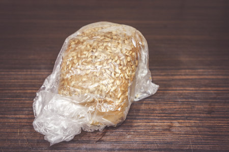 A loaf of bread with sunflower seeds inside a plastic bagの写真素材