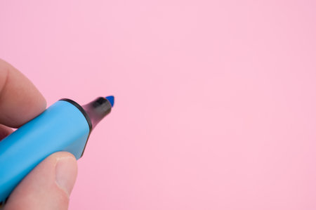 A shot of fingers holding a blue marker isolated on a bright backgroundの写真素材