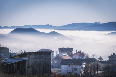 A beautiful shot of buildings and mountains above the cloudsの写真素材