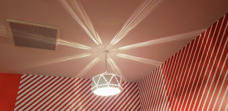 A low angle shot of an illuminated chandelier hanging in a red striped roomの写真素材