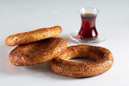 A closeup shot of freshly baked homemade simits with a cup of tea on a white surface