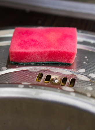 A vertical shot of a pink wet sponge near a sinkの写真素材