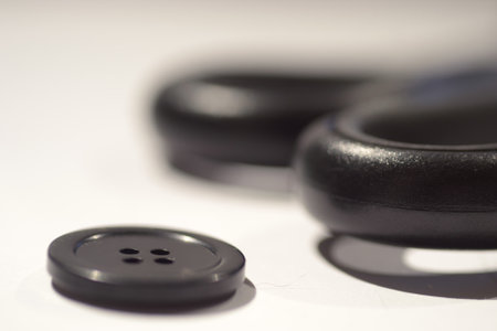 A selective focus shot of a button and scissor handle on a white surface