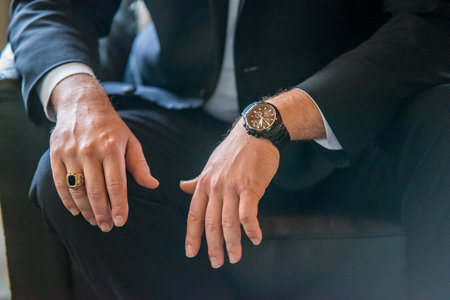 A closeup shot of a man wearing a suit, more precisely: his hands, ring, and wristwatchのeditorial素材