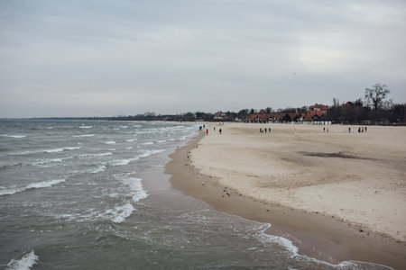 A beach surrounded by the sea and buildings under a cloudy sky at daytimeの写真素材