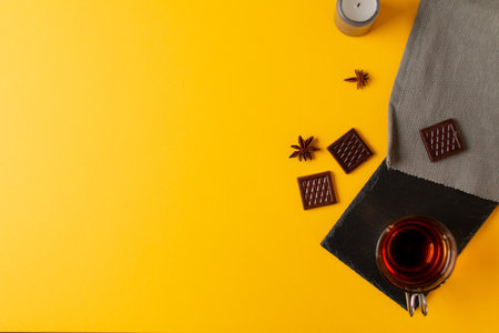 A top view of star anise tea, chocolate bars, and candle isolated on yellow backgroundの写真素材