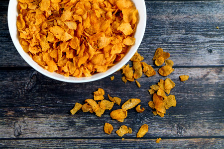 A top view of cornflakes in a bowl on a wooden table