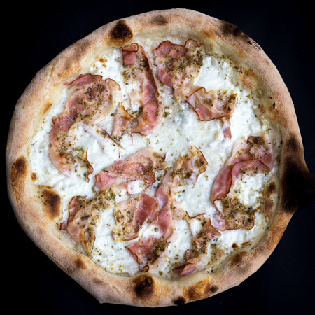 A closeup shot of an organic pizza with bacon isolated on black backgroundの写真素材