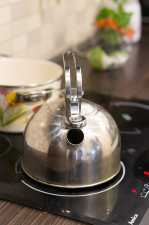 A closeup of a kettle with an open spout on an electric stoveの写真素材