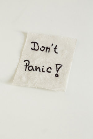 A high angle shot of a Don't panic note on a piece of paper on a white surface - panic because of Covid-19の写真素材