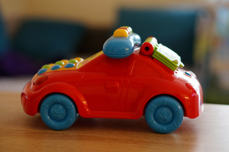 A shallow focus shot of a small plastic toy car on a table with a blurred backgroundの写真素材