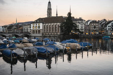 A panoramic shot of the city of Zurich along Limmat river with moored boats at a dockのeditorial素材