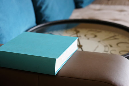 A shallow focus shot of a hardcover book placed on the armchair with a blurred backgroundの写真素材