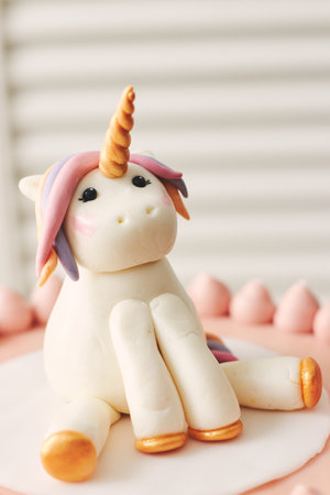 A closeup of a small unicorn on the top of a birthday cake under the lights with a blurry backgroundの写真素材