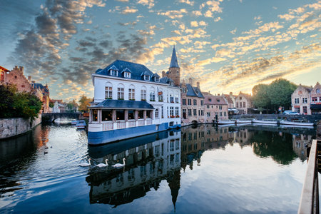 BRUGES, BELGIUM - Oct 16, 2018: Bruges Canals  at sunrise with some lovely gooses swimming in the foreground and the beautiful skiesのeditorial素材