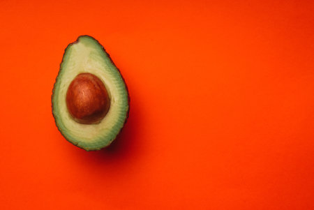 A top view of half avocado on an orange backgroundの写真素材