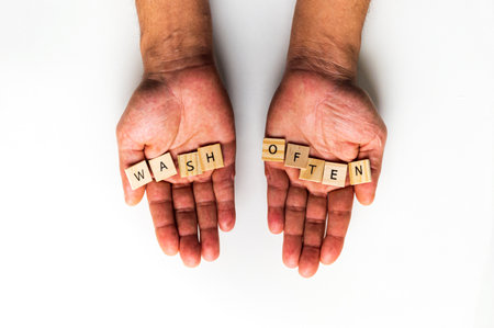 A hand of a man holding at the letters of WASH OFTEN isolated on a white backgroundの写真素材
