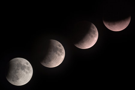 The cycle of the moon depicting a lunar eclipse against a black backgroundの写真素材