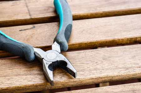 A closeup shot of metal pliers on a wooden surface