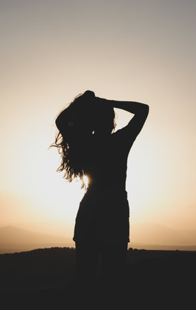 A vertical silhouette of a young female at sunsetの写真素材