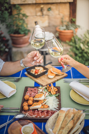 A vertical shot of clinking glasses of white wine and seafood on the tableの写真素材