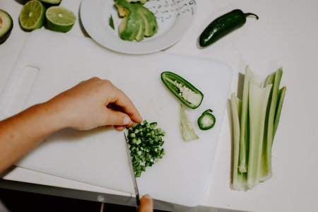 A top view of female's hand cutting green chili pepperの写真素材