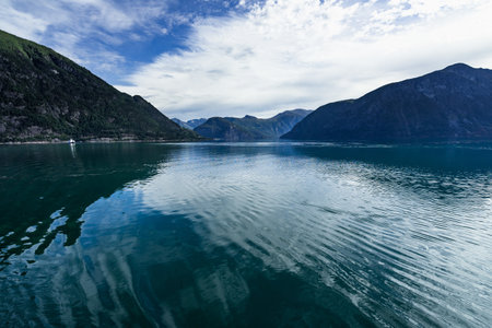 The Storfjorden surrounded by hills covered in greenery under a cloudy sky in Norwayの写真素材