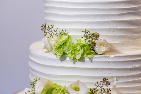 A beautiful white wedding cake with green and white floral designの写真素材