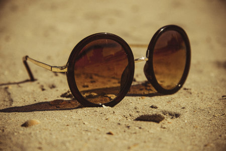 A closeup shot of sunglasses on the sandの写真素材