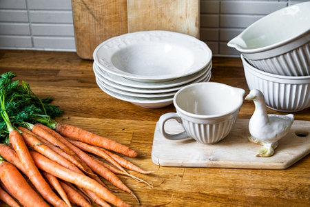 fresh carrots and and plates in kitchenの写真素材