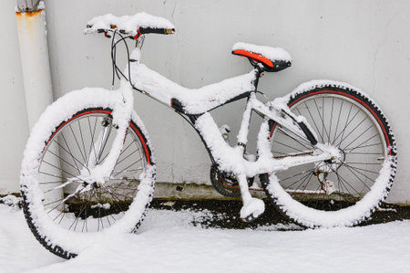 A bicycle covered with snow near the white wall in Swedenの写真素材