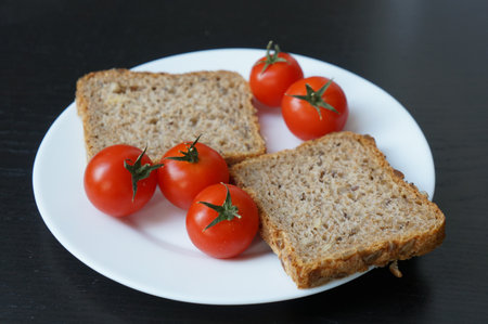 A closeup shot of cherry tomatoes and a bread slice on the plate