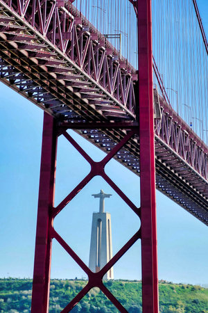 A vertical shot of a bridge with the Christ statue in the background in Lisbon, Portugalのeditorial素材