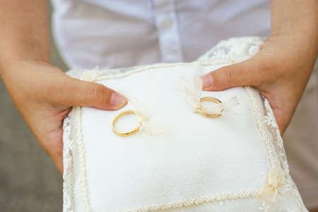 A closeup shot of golden wedding rings on a small cushion