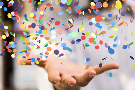 A male hand and colorful party confetti with blurred backgroundの写真素材