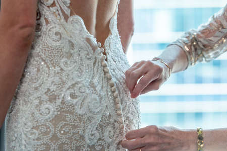 A person helping a bride wear her beautiful wedding dressの写真素材
