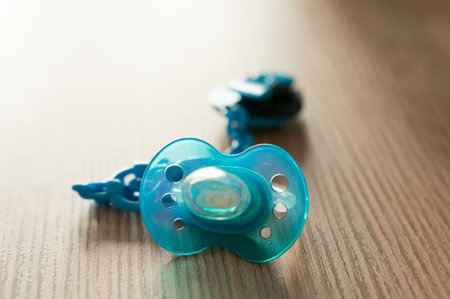 A closeup shot of a blue pacifier on a table with a blurred backgroundの写真素材