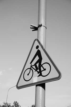 A vertical greyscale closeup shot of a street sign with a bicycle symbol on a poleの写真素材