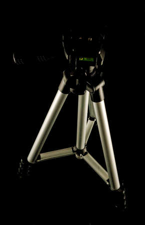 A vertical closeup shot of a tripod with a black background