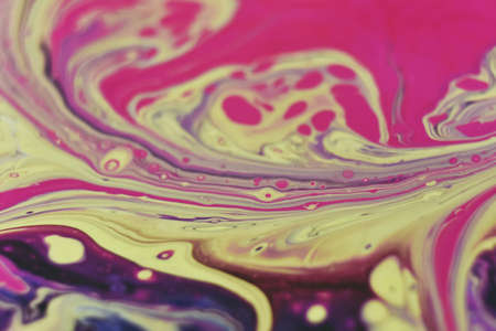 A macro shot of an abstract background of colorful acrylic paint and poured oil mixture