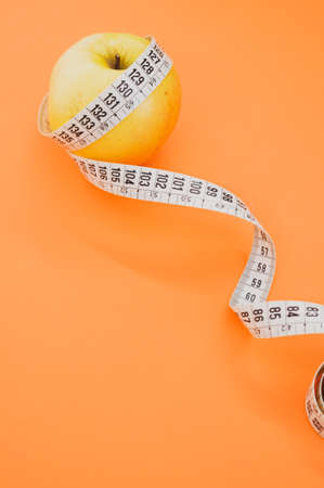 An apple with measuring tape isolated on orange background