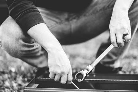 A grayscale shot of a technician holding tools from a toolboxの写真素材