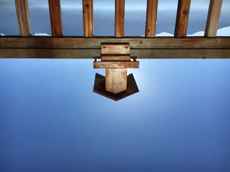 A small wooden construction on a fence resembling a house in front of the mountains