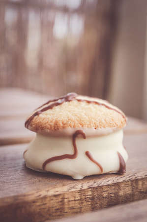 A vertical closeup shot of a cookie with white chocolate on a wooden surface