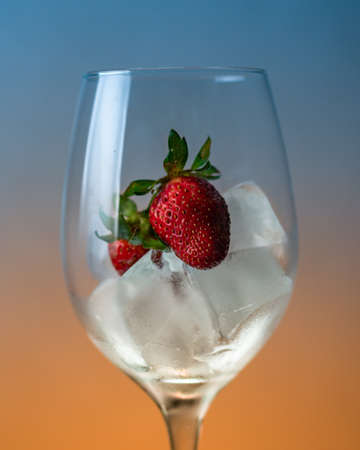 A closeup shot of a wine glass with a delicious fresh strawberry with ice with a blurred backgroundの写真素材