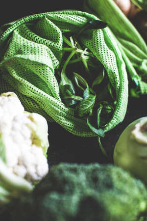 An overhead shot of different fresh  vegetables in green bags and on a dark surfaceの写真素材