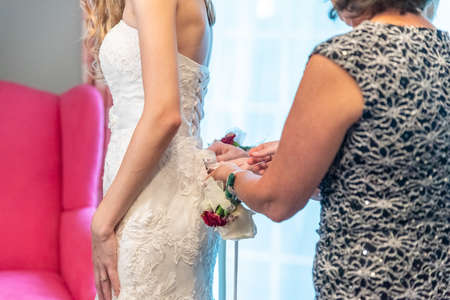 A closeup shot of bridesmaid is helping the bride to dressの写真素材