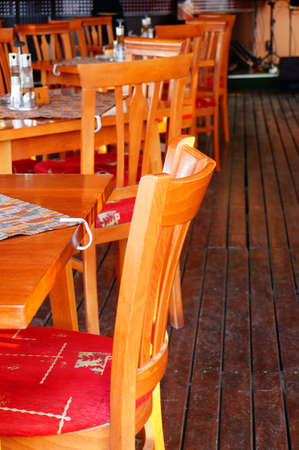 A vertical image of a row of restaurant wooden chairs on a wooden floor