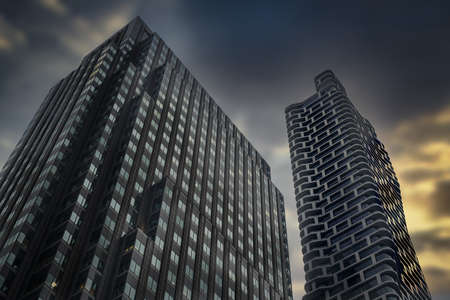A low angle view of modern skyscrapers under a cloudy sky during the sunset in the evening